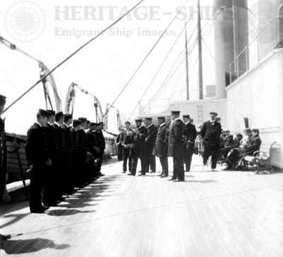 Captain Henry St. George Lindsay and his officers inspecting a lifeboat crew on the deck of the Celtic on a voyage from Liverpool to New York in June 1904
